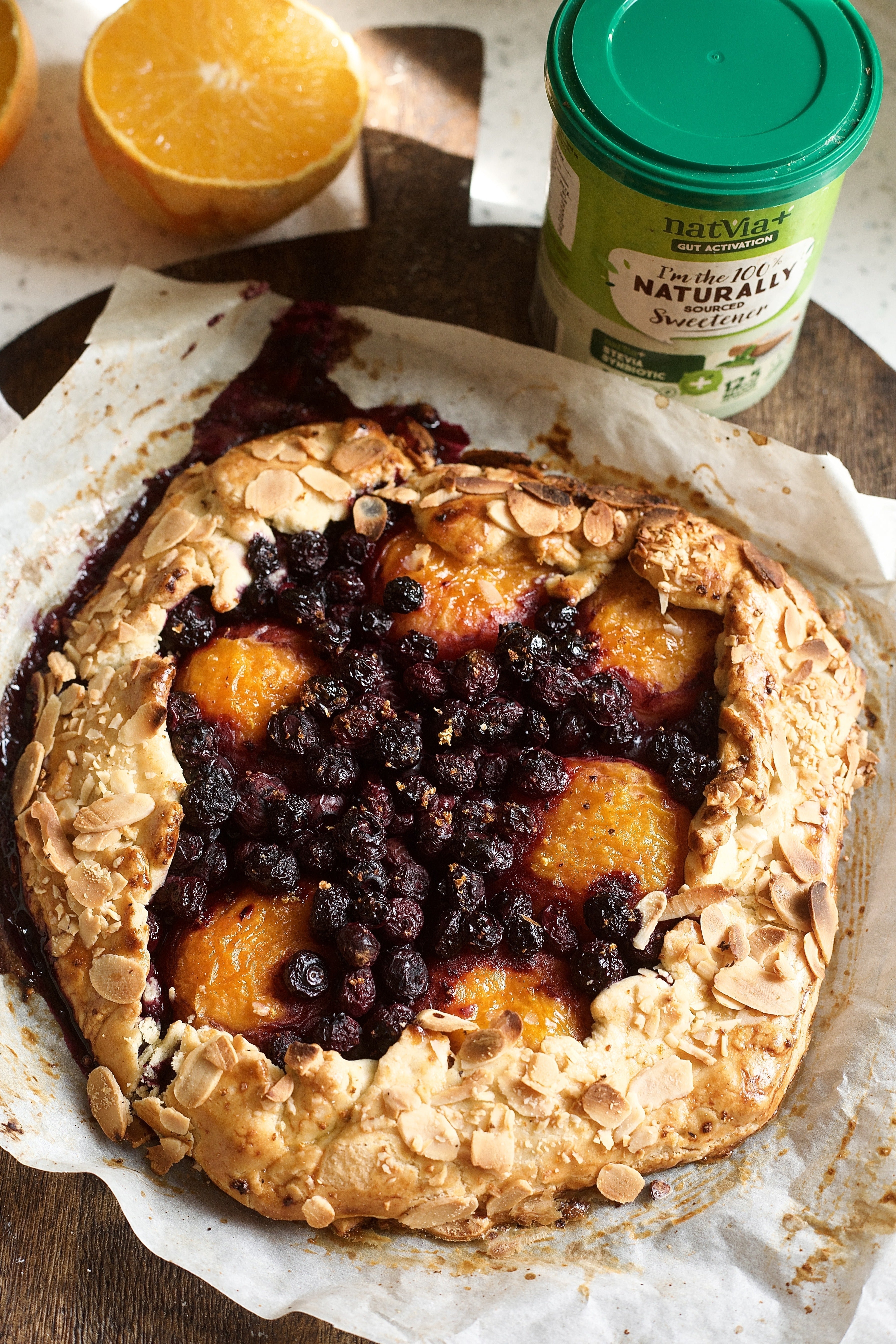 One big Cardamom Blueberry & Apricot Rustic Galette serving. Alongside natvia natural sweetener and an orange on the side.