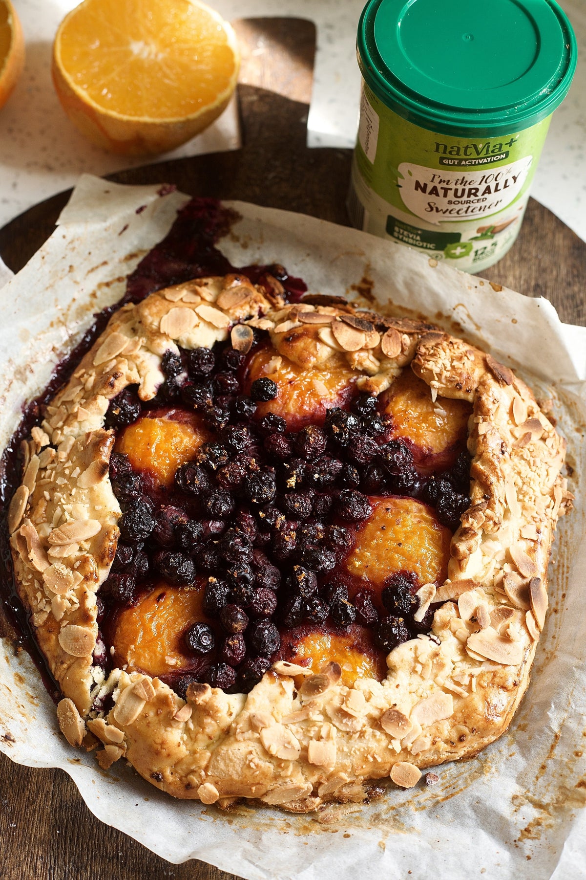 One big Cardamom Blueberry & Apricot Rustic Galette serving. Alongside natvia natural sweetener and an orange on the side. 
