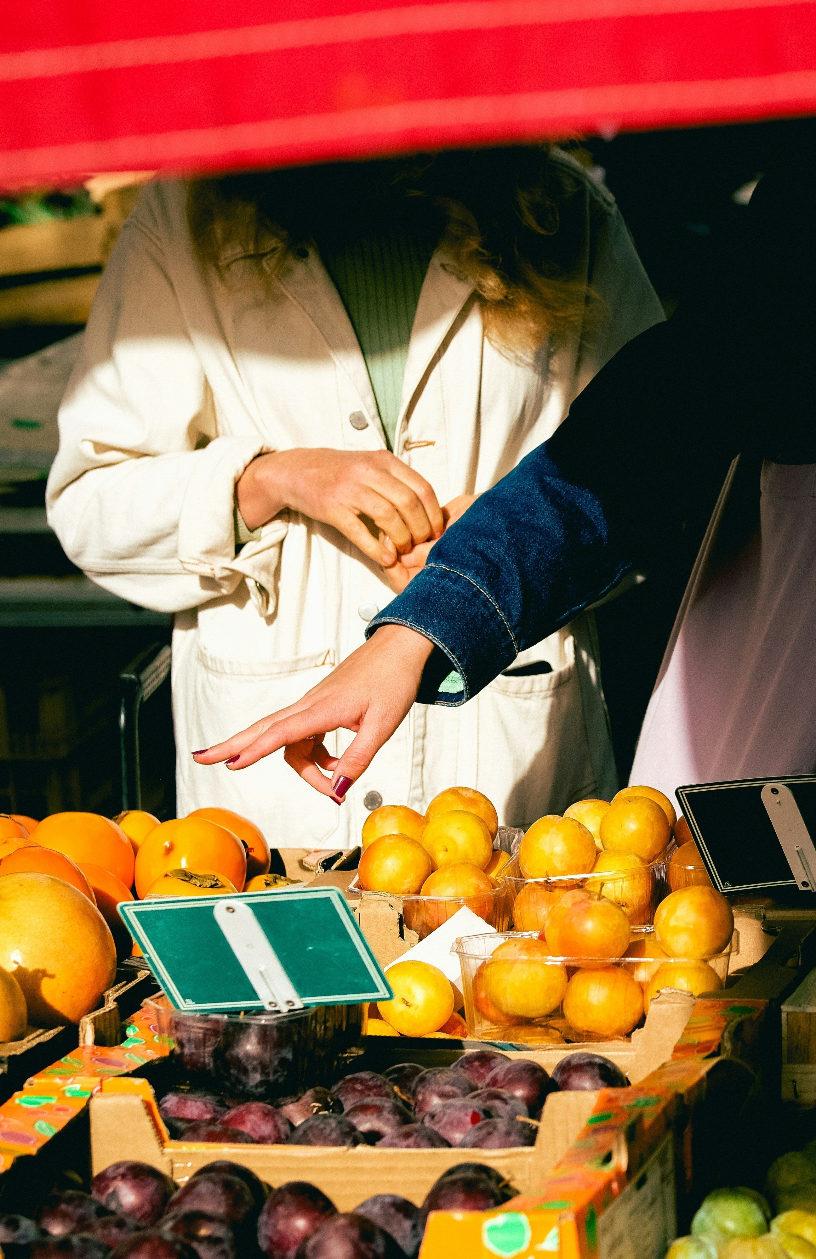Two girls are shopping at a market, selecting fresh spring produce for healthy eating.