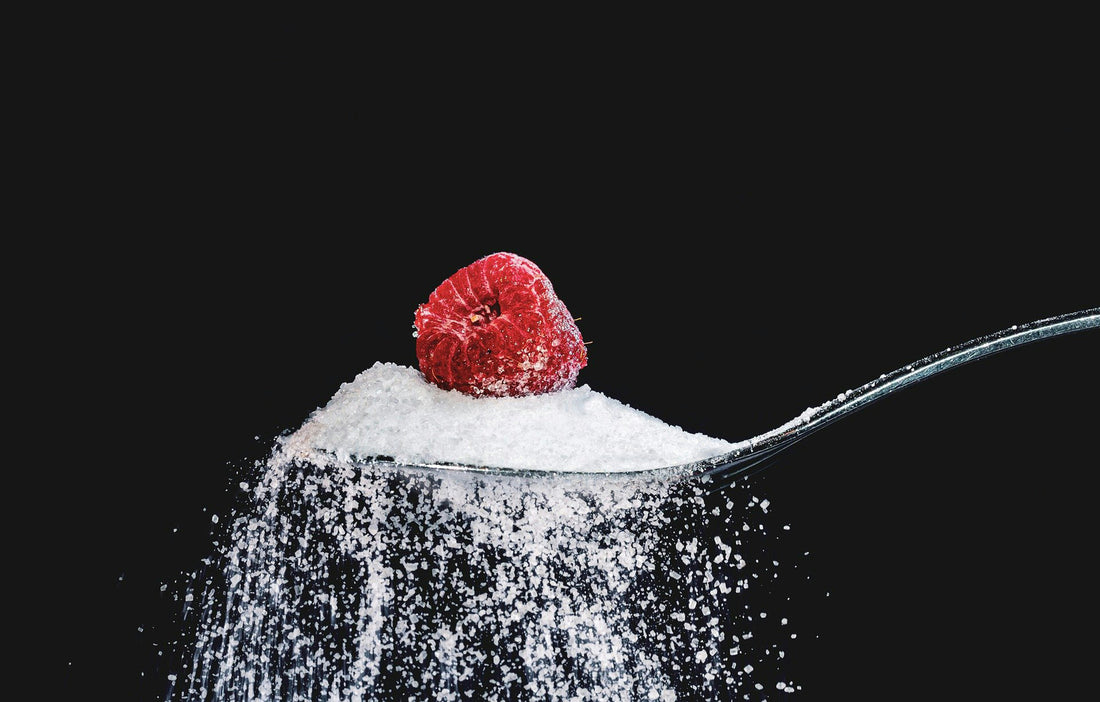 A spoonful of sugar with a cranberry on top with black background.