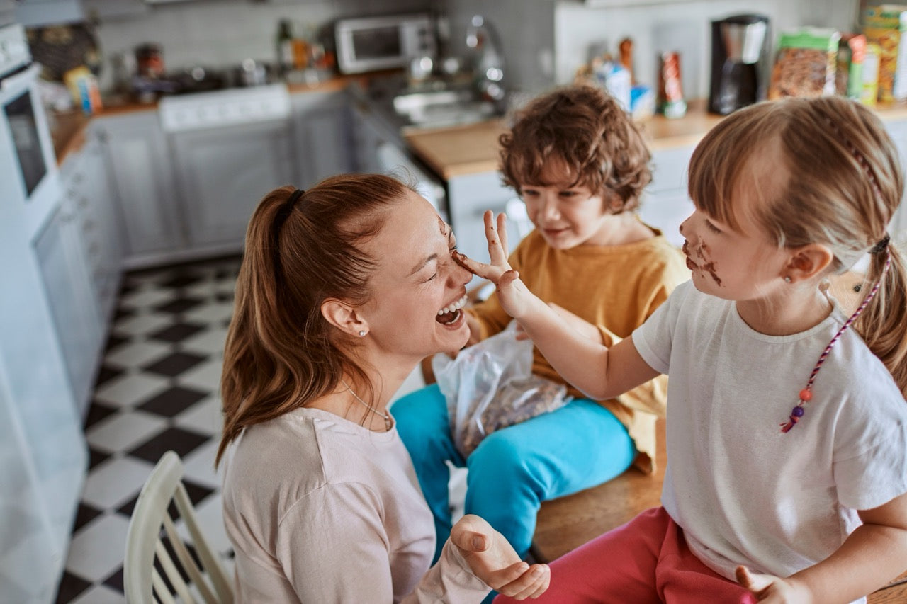 Mother and children having fun with chocolate in the kitchen