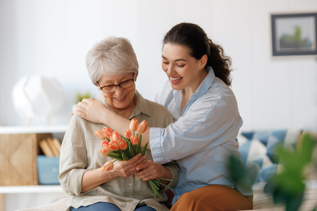 Young woman and her mother with flowers tulips in hands at home.