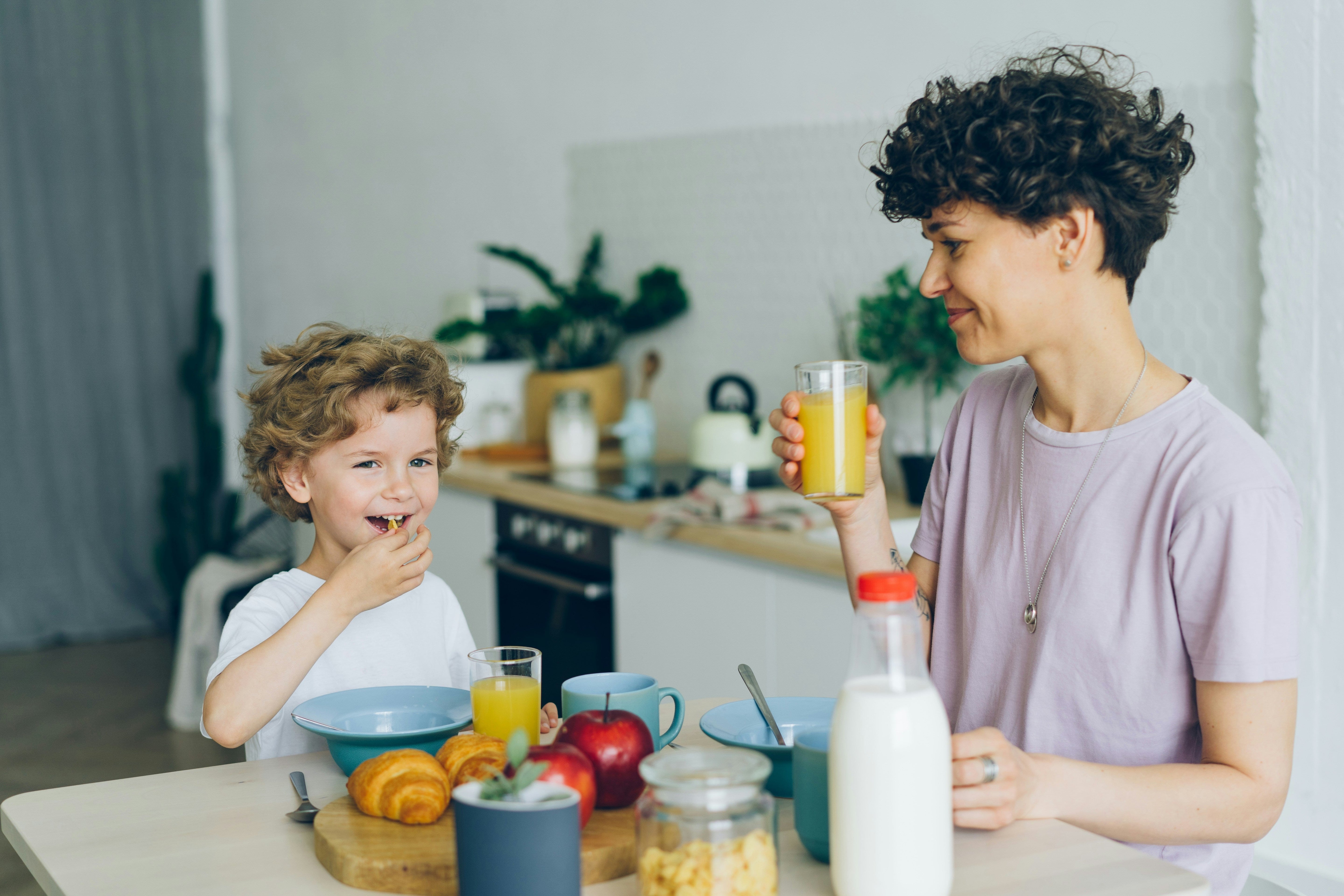 Mother and son drinking orange juice in the dining table for their gut health